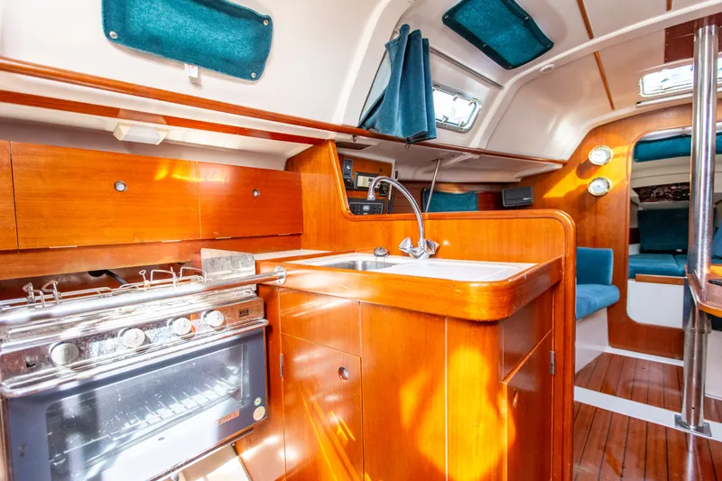 Slide: The Image of Interior of 1995 Beneteau Oceanis 321 sailboat with wooden cabinetry and compact kitchen area. - 48