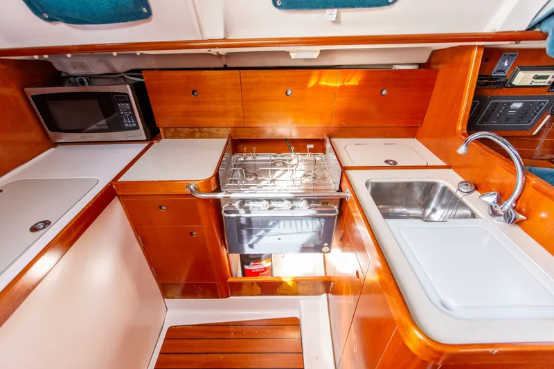 Slide: The Image of 1995 Beneteau Oceanis 321 yacht kitchen with stove, sink, and microwave. - 49