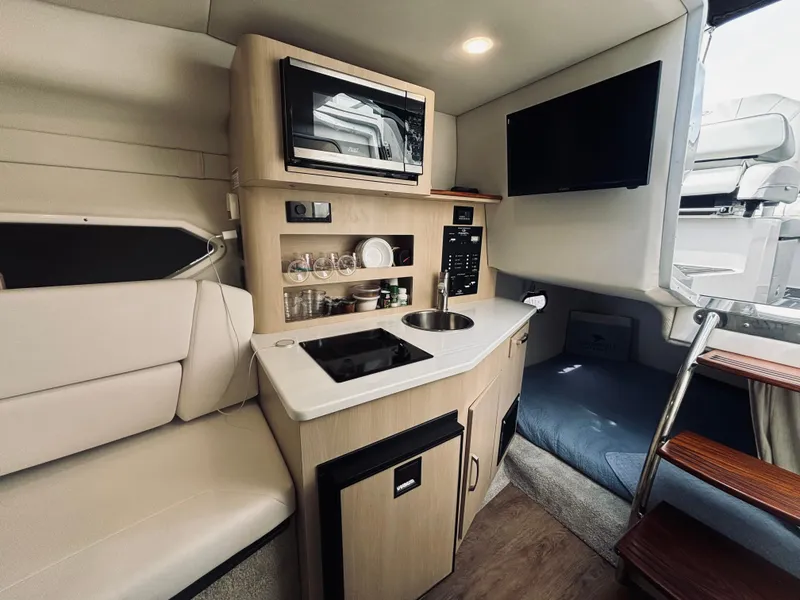 Slide: The Image of 2023 Regal 26XO boat interior with kitchenette, microwave, sink, and seating area. - 10