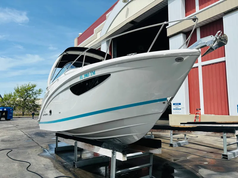 Slide: The Image of 2023 Regal 26XO boat on a stand outside a red and white building. - 2