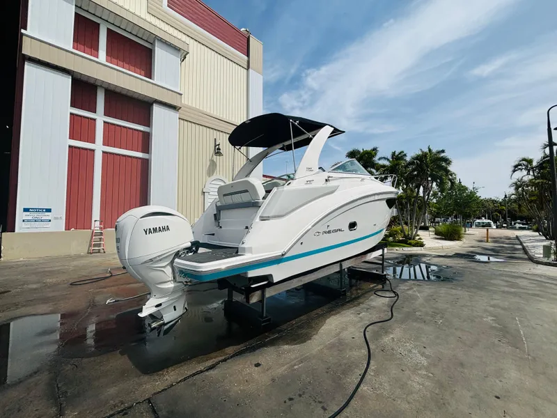 Slide: The Image of 2023 Regal 26XO boat with Yamaha engine, docked outdoors near a building. - 3