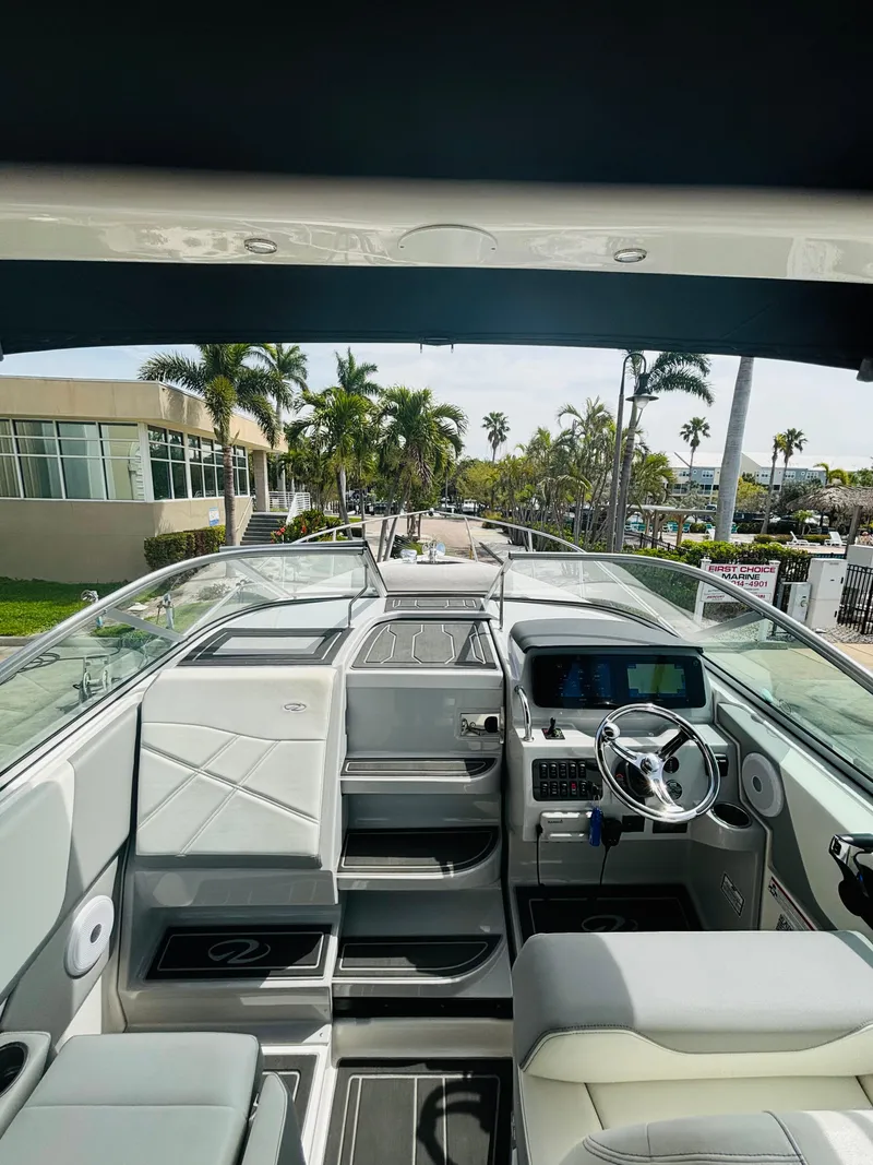 Slide: The Image of 2023 Regal 26XO boat interior with modern dashboard and seating, surrounded by palm trees. - 6