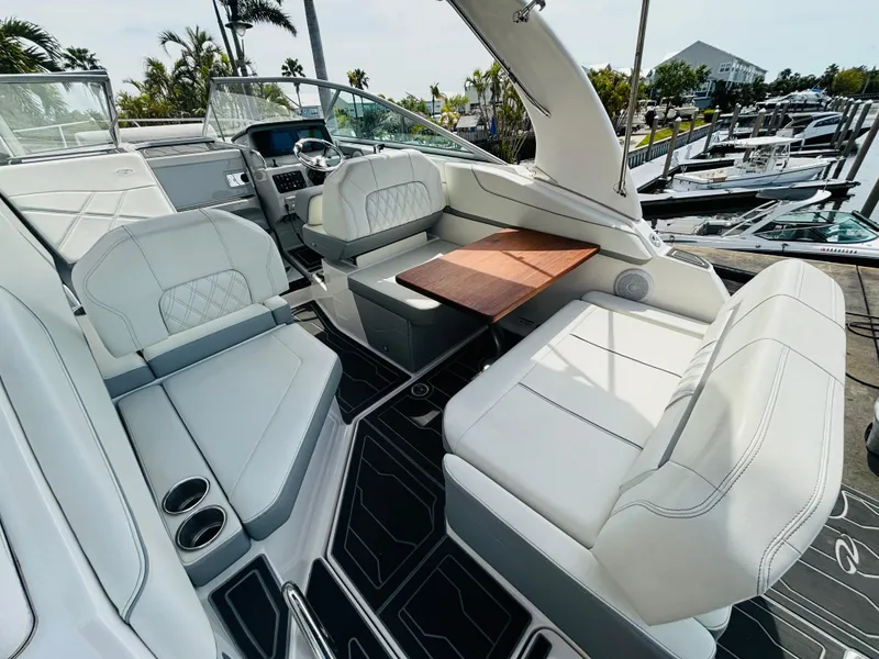 Slide: The Image of 2023 Regal 26XO boat interior with white seating and wooden table, docked at marina. - 8
