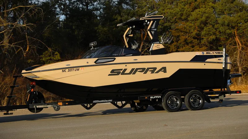 Slide: The Image of 2023 Supra SL boat on trailer, parked outdoors, showcasing sleek design and modern features. - 17