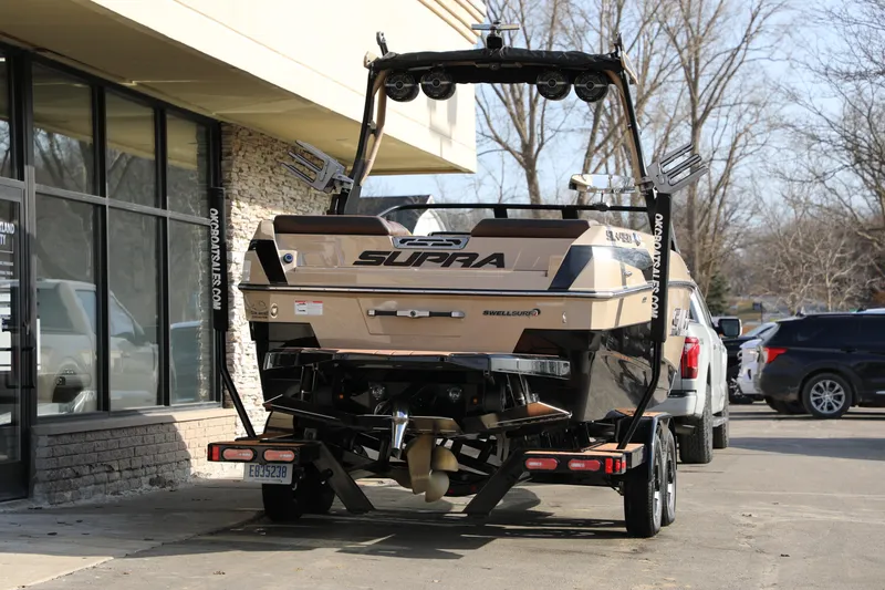 Slide: The Image of 2023 Supra SL boat on trailer, parked outside a building, showcasing rear design. - 28