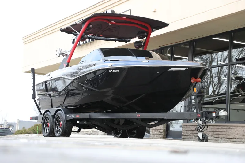 Slide: The Image of 2023 Malibu Wakesetter 22 LSV boat on trailer, black exterior, red accents, parked outside. - 11