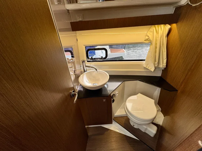 Slide: The Image of 2023 Jeanneau NC 1095 Fly bathroom with sink, toilet, and window view. - 15