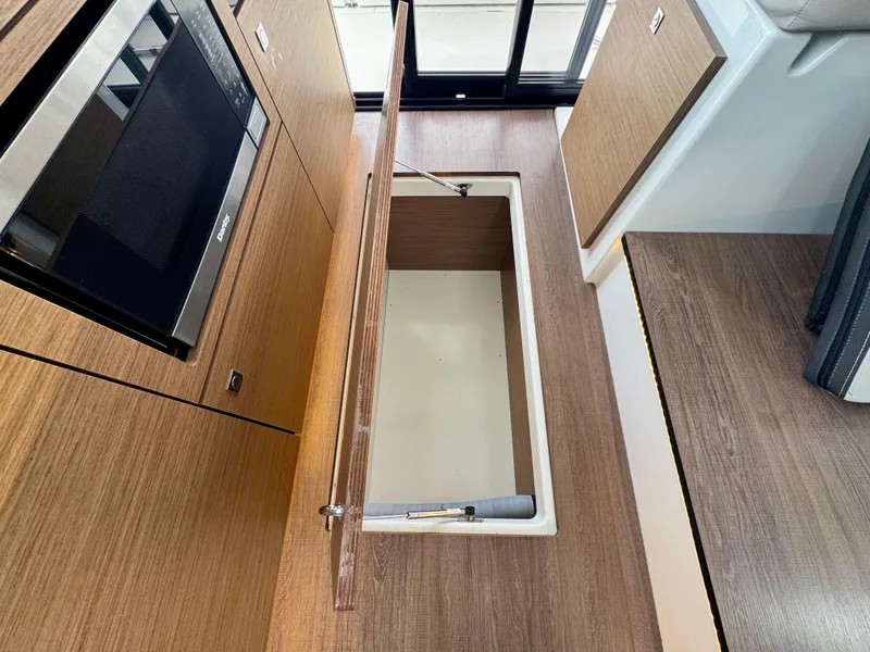 Slide: The Image of 2023 Jeanneau NC 1095 Fly interior with open storage compartment and microwave. - 7