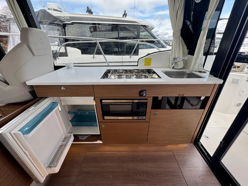 Slide: The Image of 2023 Jeanneau NC 1095 Fly yacht kitchen with stove, sink, microwave, and open fridge. - 9