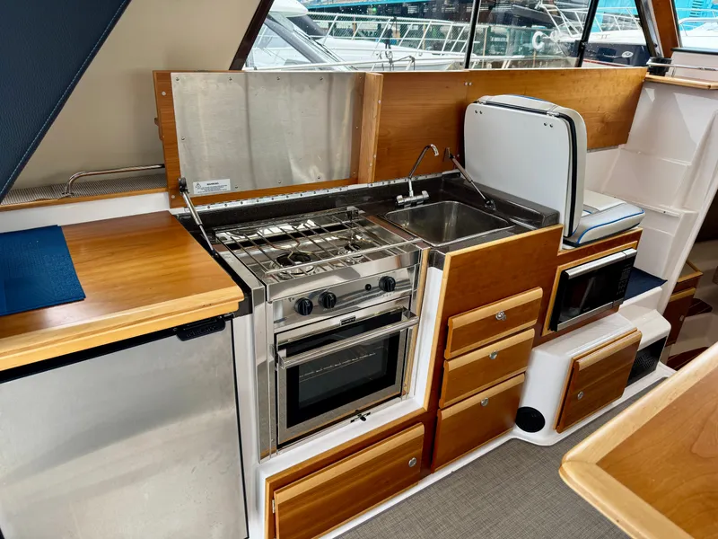 Slide: The Image of 2018 Cutwater C-30 CB boat kitchen with stove, sink, and wooden cabinetry. - 12