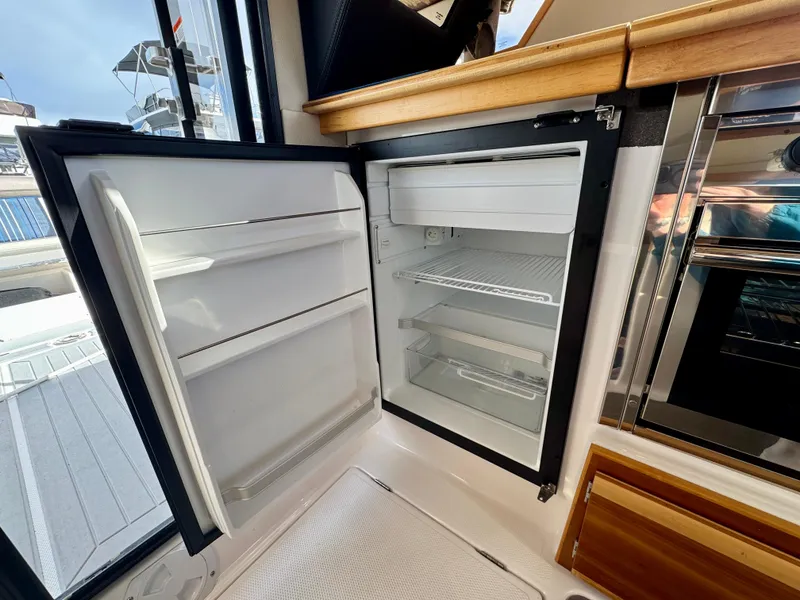 Slide: The Image of Open refrigerator inside 2018 Cutwater C-30 CB boat, showcasing interior shelves and freezer compartment. - 13
