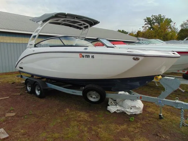 Slide: The Image of 2023 Yamaha Boats 252SD on trailer, parked outdoors near a building. - 1