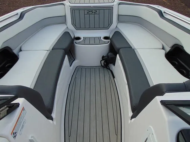 Slide: The Image of 2023 Yamaha Boats 252SD interior with gray seating and flooring, featuring cup holders. - 19