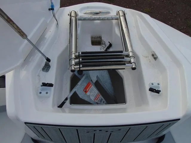 Slide: The Image of 2023 Yamaha Boats 252SD anchor storage with ladder, open compartment view. - 23