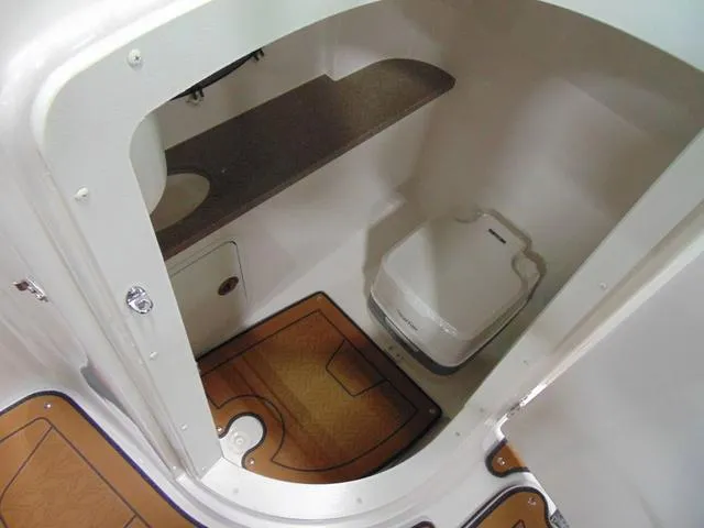 Slide: The Image of 2025 Hurricane SunDeck 2486 OB boat interior with compact bathroom and wooden flooring. - 6