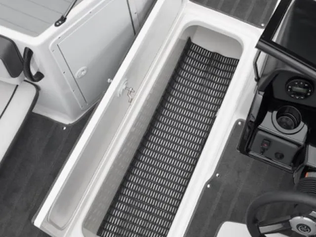 Slide: The Image of 2025 Yamaha Boats AR190 interior storage compartment with black mat and dashboard view. - 5