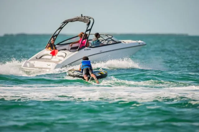 Slide: The Image of 2025 Yamaha Boats AR195 cruising with water sports enthusiast in vibrant ocean setting. - 6
