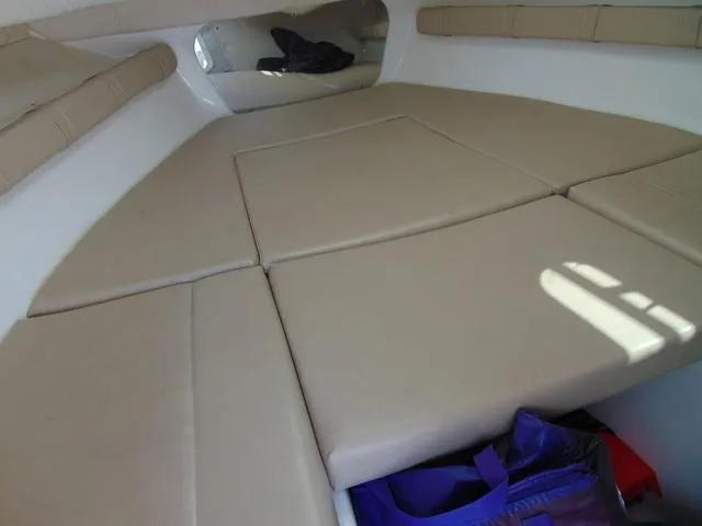 Slide: The Image of 2011 Sea Chaser 2100 Walk-Around cabin interior with beige cushions and storage space. - 17