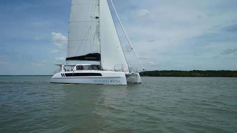 Slide: The Image of 2025 Seawind 1160 XL catamaran sailing on calm waters under a clear sky. - 2