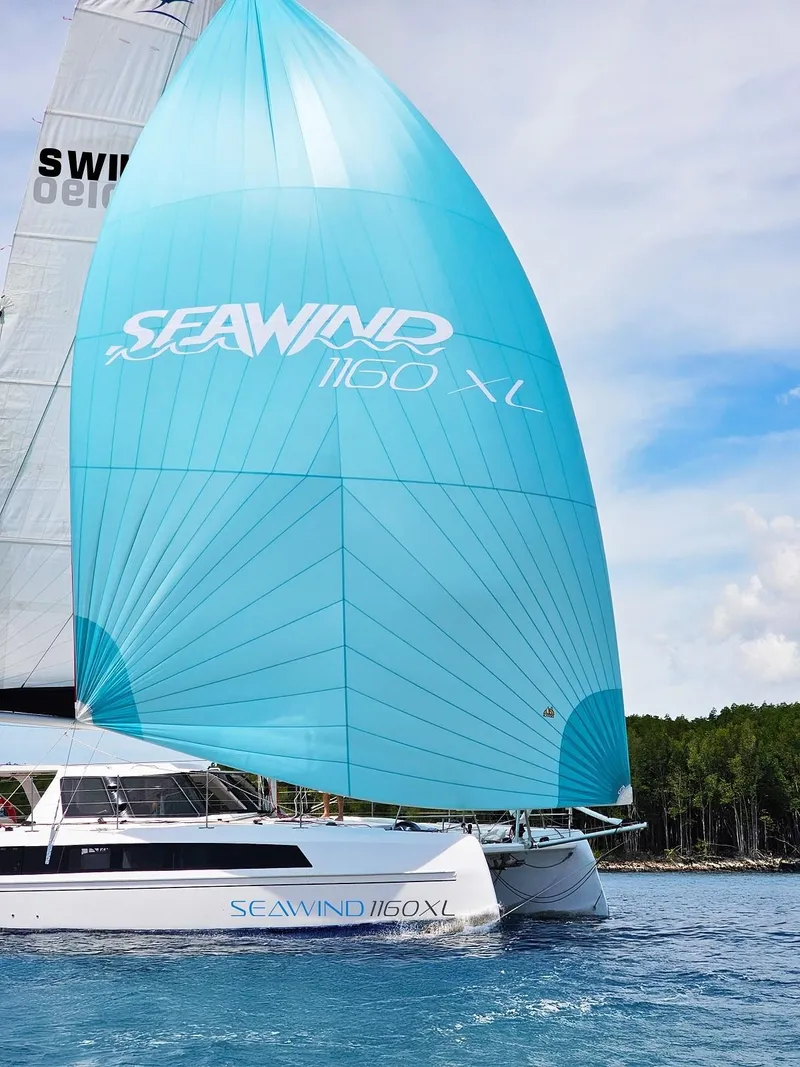 Slide: The Image of 2025 Seawind 1160 XL catamaran sailing with blue spinnaker on a sunny day. - 3