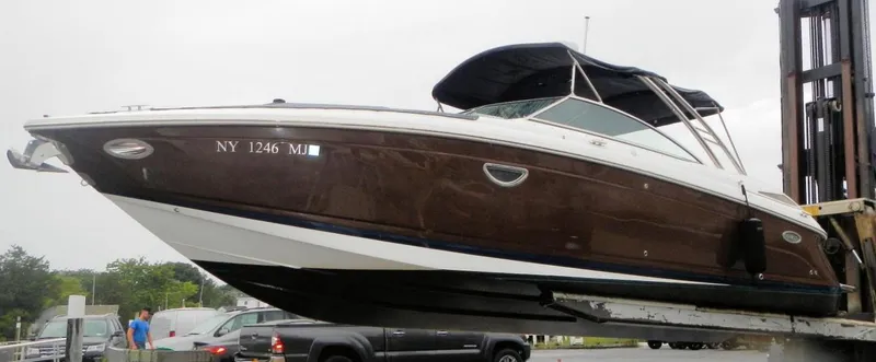 The Image of 2015 Cobalt 302 boat on forklift, brown hull, dockside view. - 0