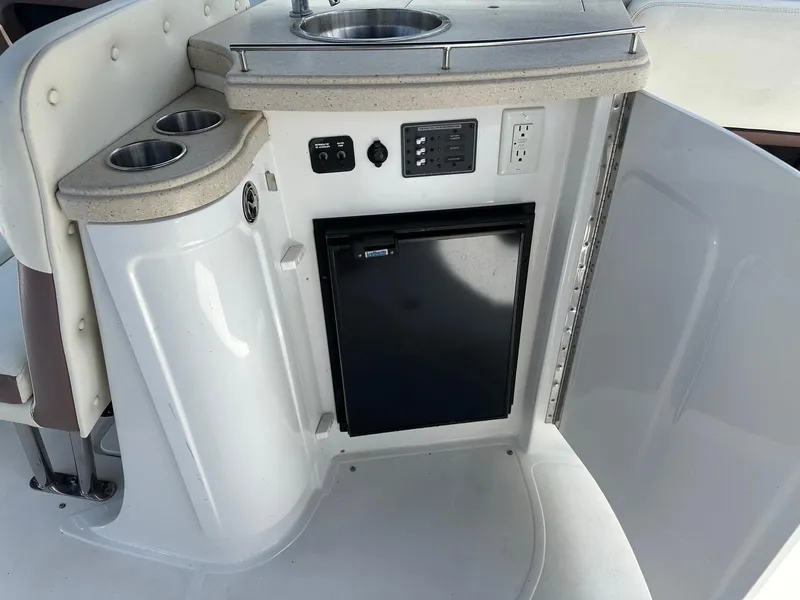 Slide: The Image of 2012 Cobalt 302 boat kitchenette with sink, mini fridge, and cup holders. - 16