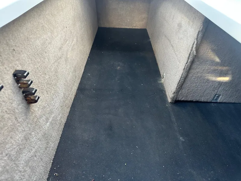 Slide: The Image of Interior storage compartment of a 2012 Cobalt 302 boat, featuring carpeted walls and a rubber floor. - 20