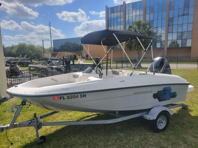 Slide: The Image of 2019 Bayliner Element E16 boat on trailer, parked outdoors under a sunny sky. - 1