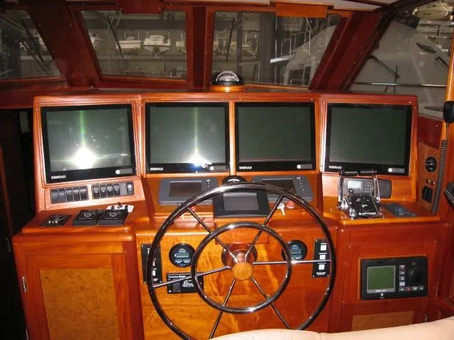 Slide: The Image of 2009 Hugh Saint 65 Commuter boat dashboard with multiple navigation screens and wooden steering wheel. - 12