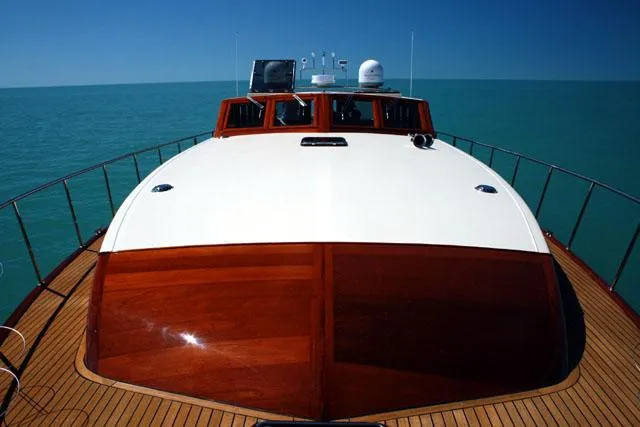 Slide: The Image of 2009 Hugh Saint 65 Commuter yacht on calm sea, showcasing sleek wooden deck and modern design. - 4
