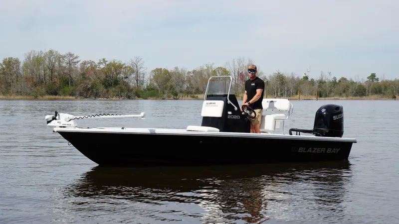 The Image of A person on a 2022 Blazer Bay 2020 boat in a calm lake setting. - 1