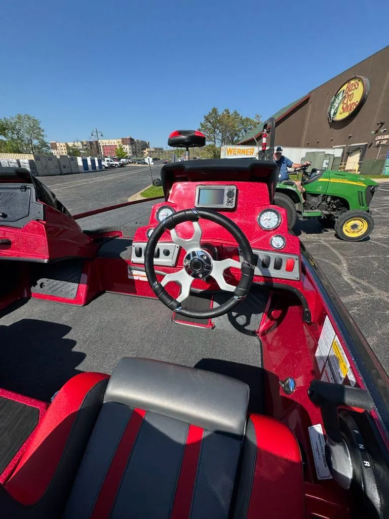 Slide: The Image of Red 2025 Nitro Z19 boat interior with steering wheel and dashboard, parked outdoors. - 6