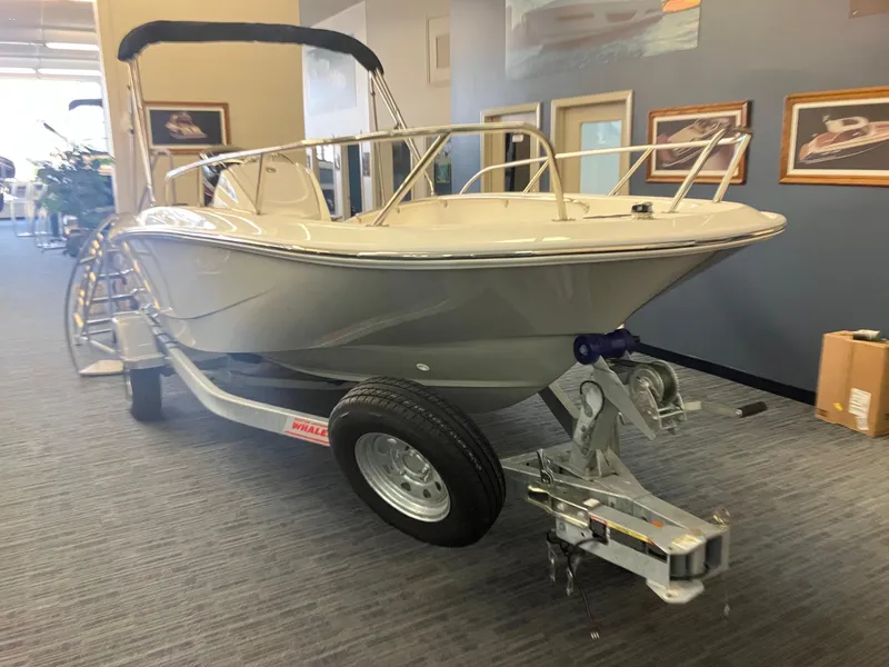 The Image of 2025 Boston Whaler 160 Super Sport boat on display indoors, showcasing sleek design and trailer. - 0