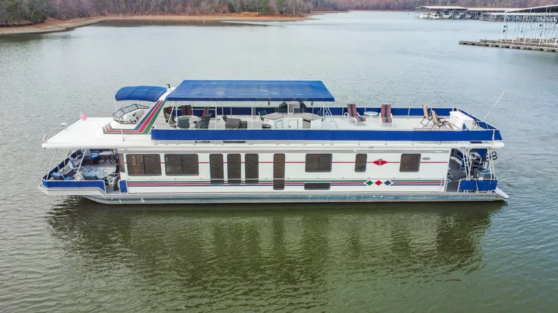 Slide: The Image of 1997 Stardust Cruisers 72x16 houseboat with blue canopy on a calm lake. - 0