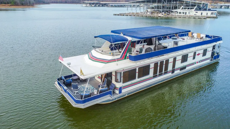 Slide: The Image of 1997 Stardust Cruisers 72x16 houseboat on a calm lake with marina in background. - 1