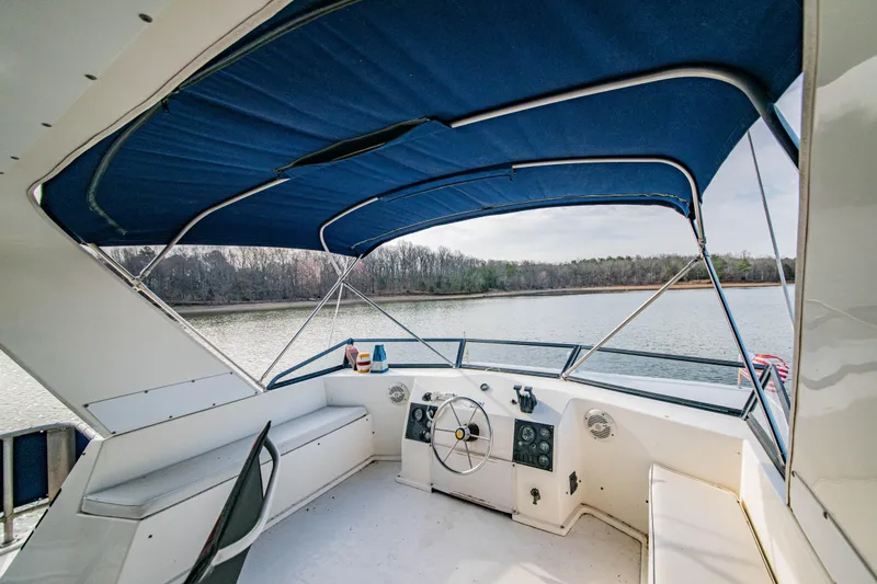 Slide: The Image of 1997 Stardust Cruisers 72x16 houseboat helm with blue canopy on a serene lake. - 14