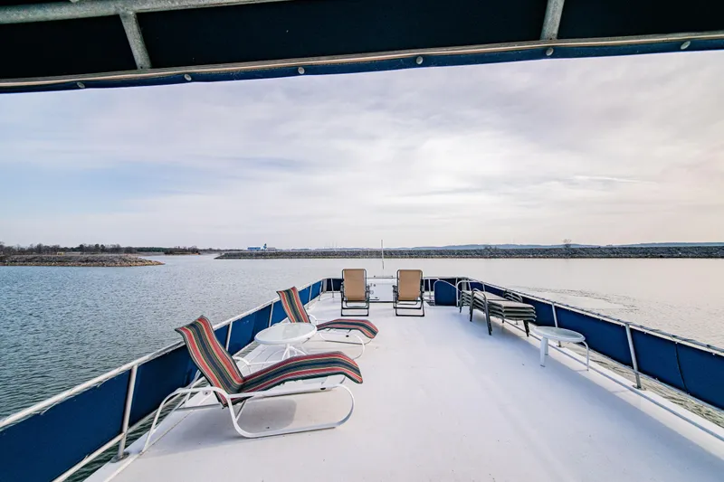 Slide: The Image of Spacious deck of 1997 Stardust Cruisers 72x16 houseboat with lounge chairs on a serene lake. - 16