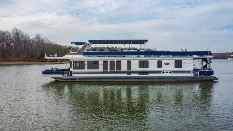 Slide: The Image of 1997 Stardust Cruisers 72x16 houseboat on a calm lake with wooded shoreline. - 2