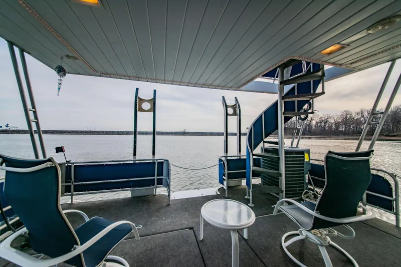 Slide: The Image of 1997 Stardust Cruisers 72x16 houseboat deck with spiral staircase and seating, overlooking serene water. - 21