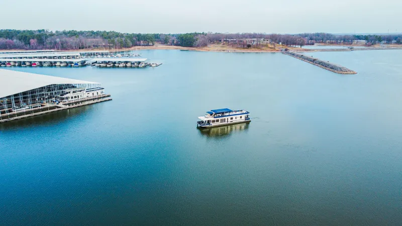 Slide: The Image of Aerial view of 1997 Stardust Cruisers 72x16 houseboat on a serene lake near a marina. - 23