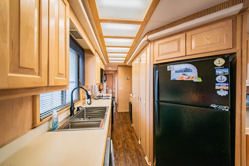 Slide: The Image of Kitchen interior of a 1997 Stardust Cruisers 72x16 houseboat with wooden cabinets and black fridge. - 32