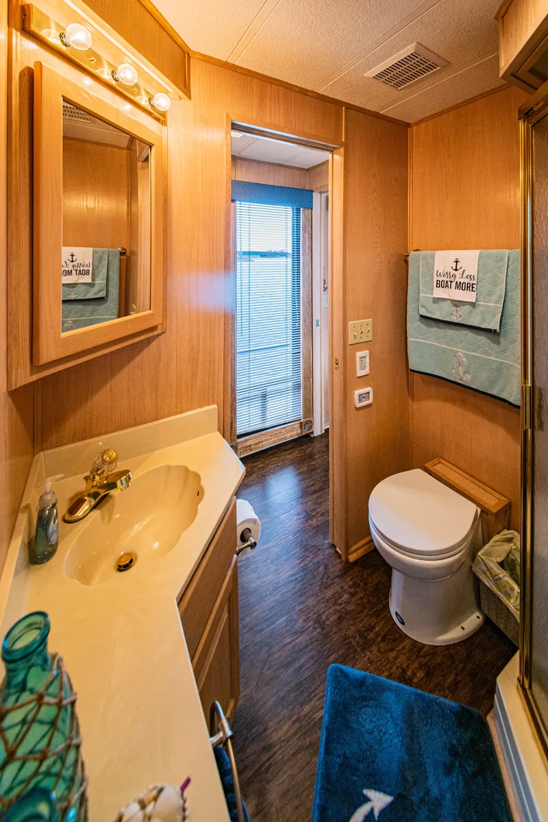 Slide: The Image of Bathroom interior of 1997 Stardust Cruisers 72x16 houseboat, featuring wood paneling and nautical decor. - 43