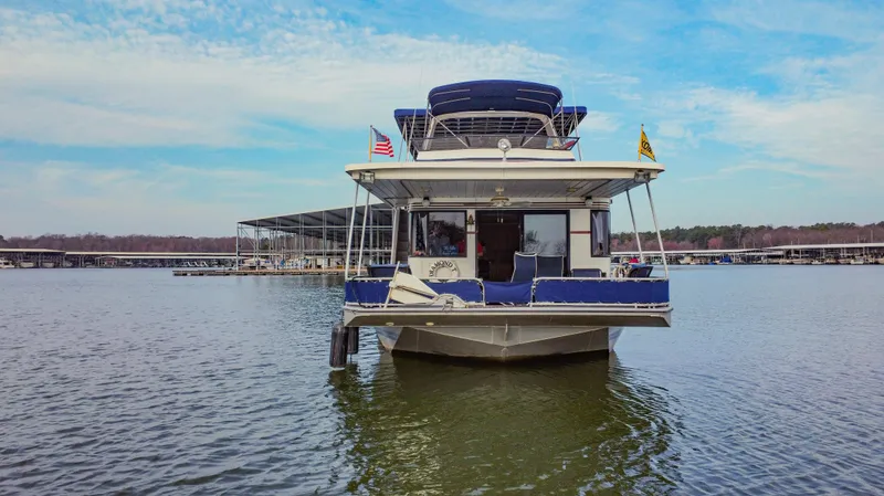 Slide: The Image of 1997 Stardust Cruisers 72x16 houseboat docked on a calm lake under a blue sky. - 7