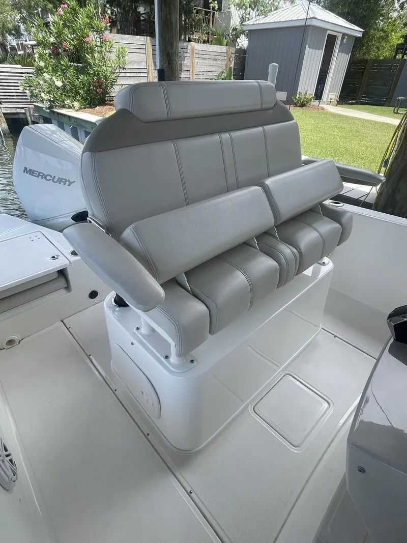 Slide: The Image of 2022 Boston Whaler 220 Dauntless boat seating with Mercury engine in a marina setting. - 11