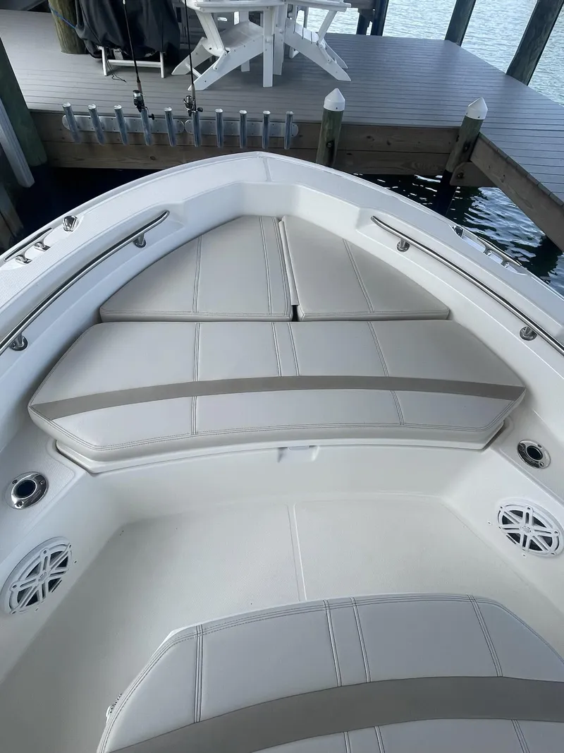 Slide: The Image of 2022 Boston Whaler 220 Dauntless boat interior with cushioned seating and dock view. - 17