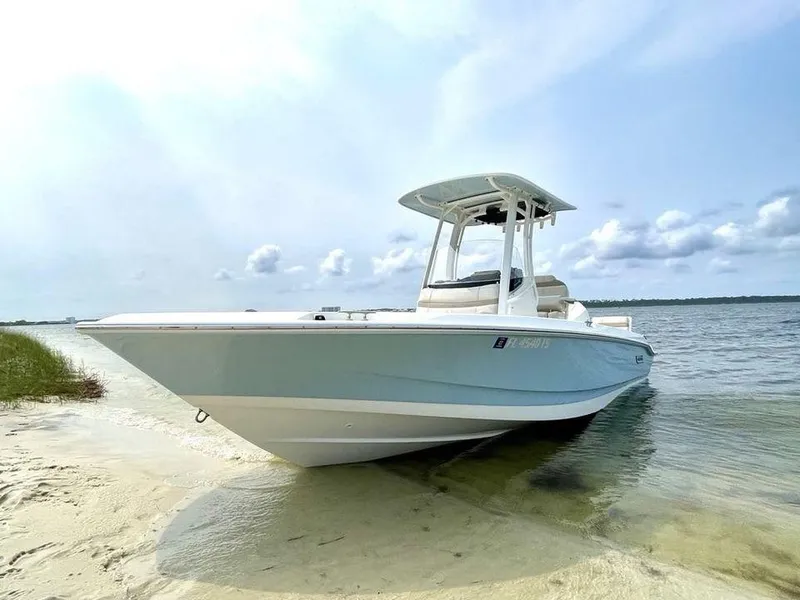 Slide: The Image of 2022 Boston Whaler 220 Dauntless boat on sandy shore with calm water background. - 2