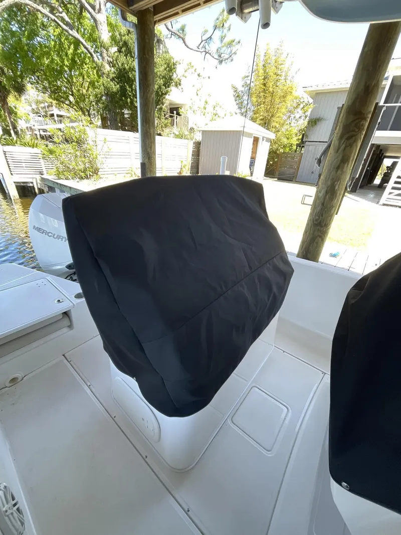 Slide: The Image of 2022 Boston Whaler 220 Dauntless boat with covered seating, docked near waterfront homes. - 21