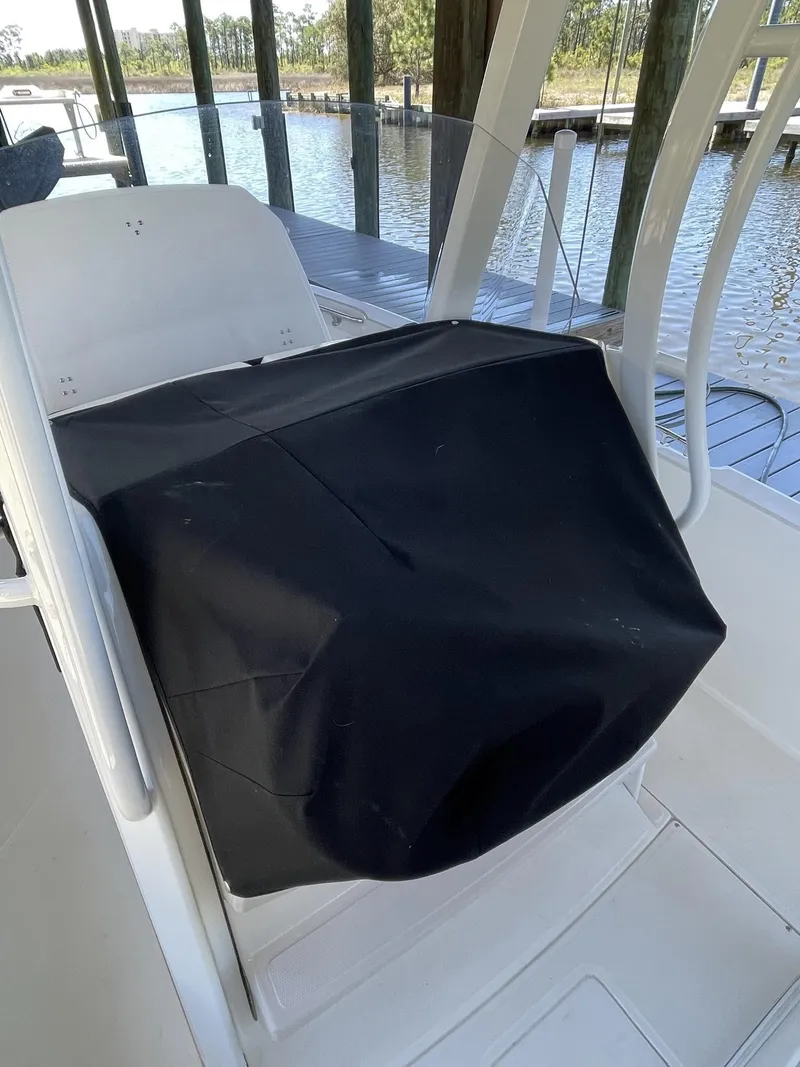 Slide: The Image of 2022 Boston Whaler 220 Dauntless boat console with black cover, docked by the water. - 22