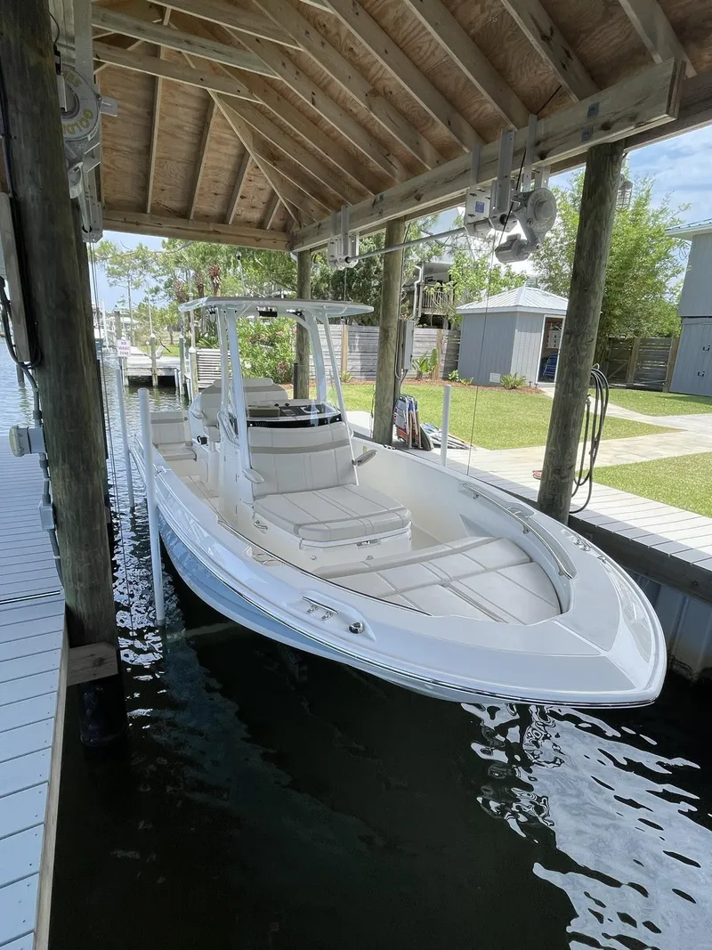 Slide: The Image of 2022 Boston Whaler 220 Dauntless boat docked under a wooden shelter. - 4
