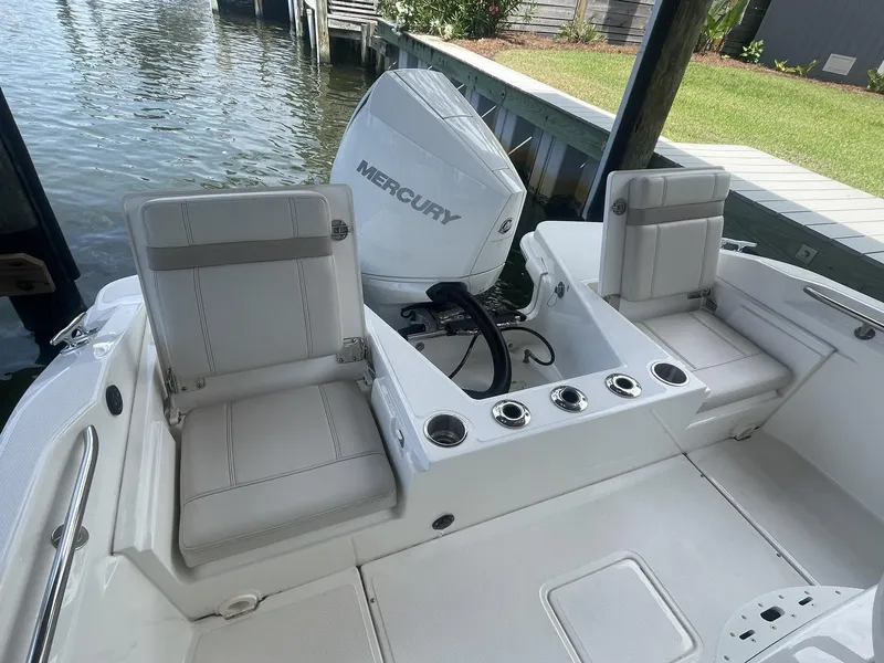 Slide: The Image of 2022 Boston Whaler 220 Dauntless boat interior with Mercury engine, docked by the water. - 9